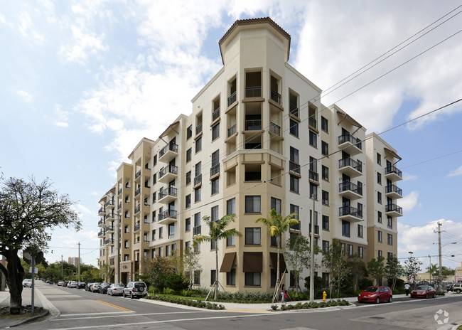 Modern urban apartment building with balconies and palm trees.