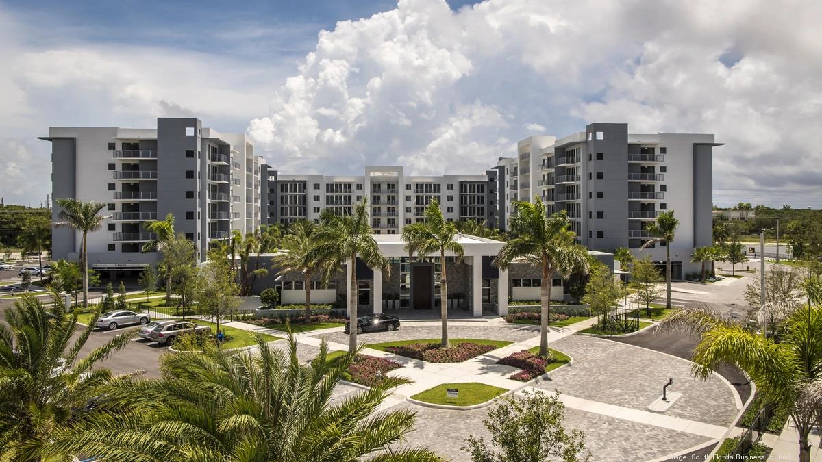 Modern residential complex with palm trees and a bright blue sky