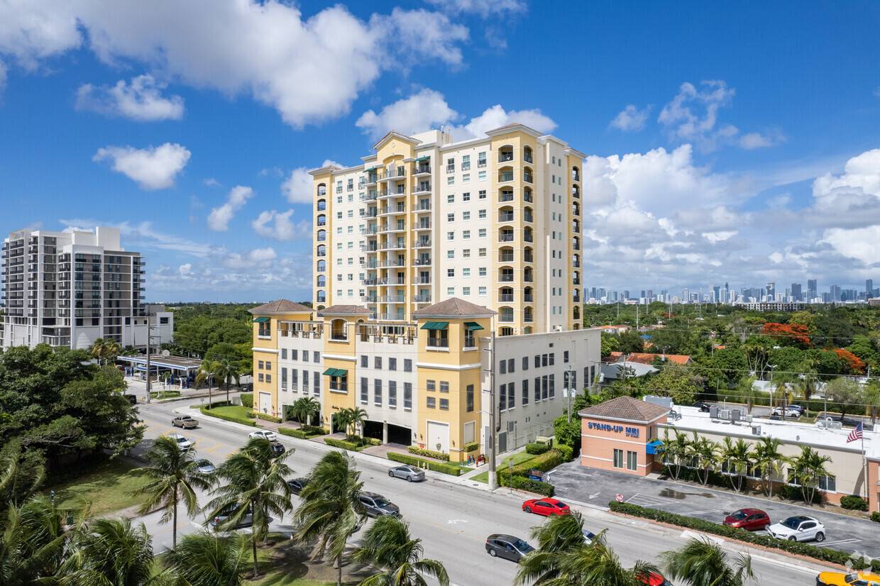 Modern apartment building with palm trees and a vibrant cityscape background.