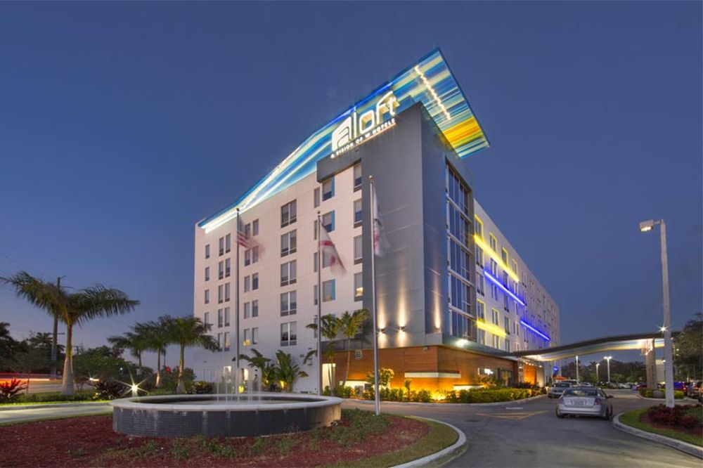 Modern hotel exterior at twilight with sleek design and illuminated signage.