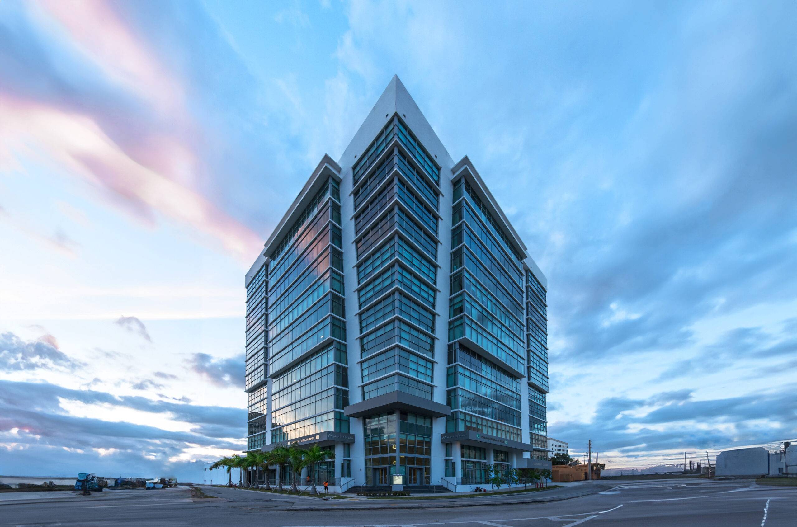 Modern glass skyscraper against a vibrant evening sky.