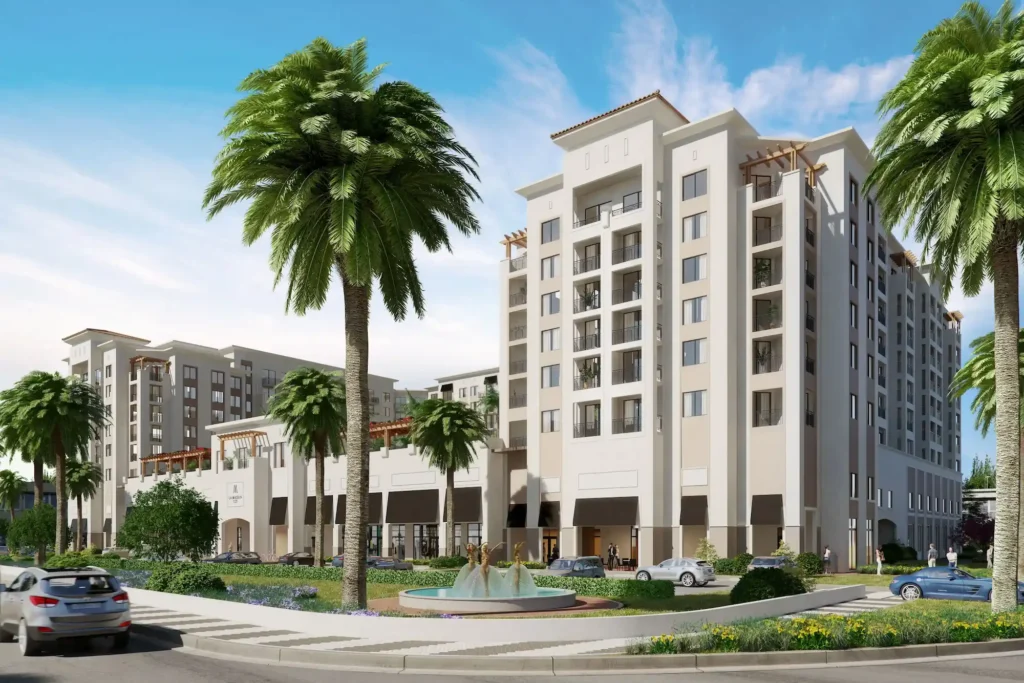 Modern apartment complex with palm trees and cars on a sunny day.
