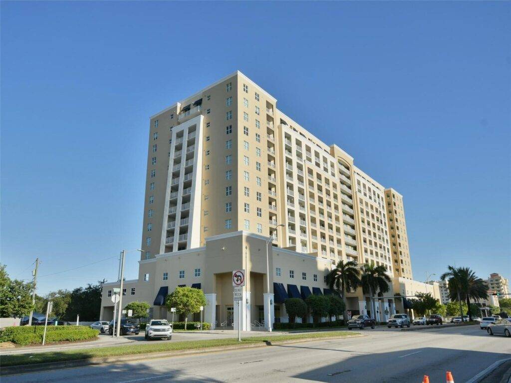 Modern Mediterranean-style apartment building under a clear blue sky.