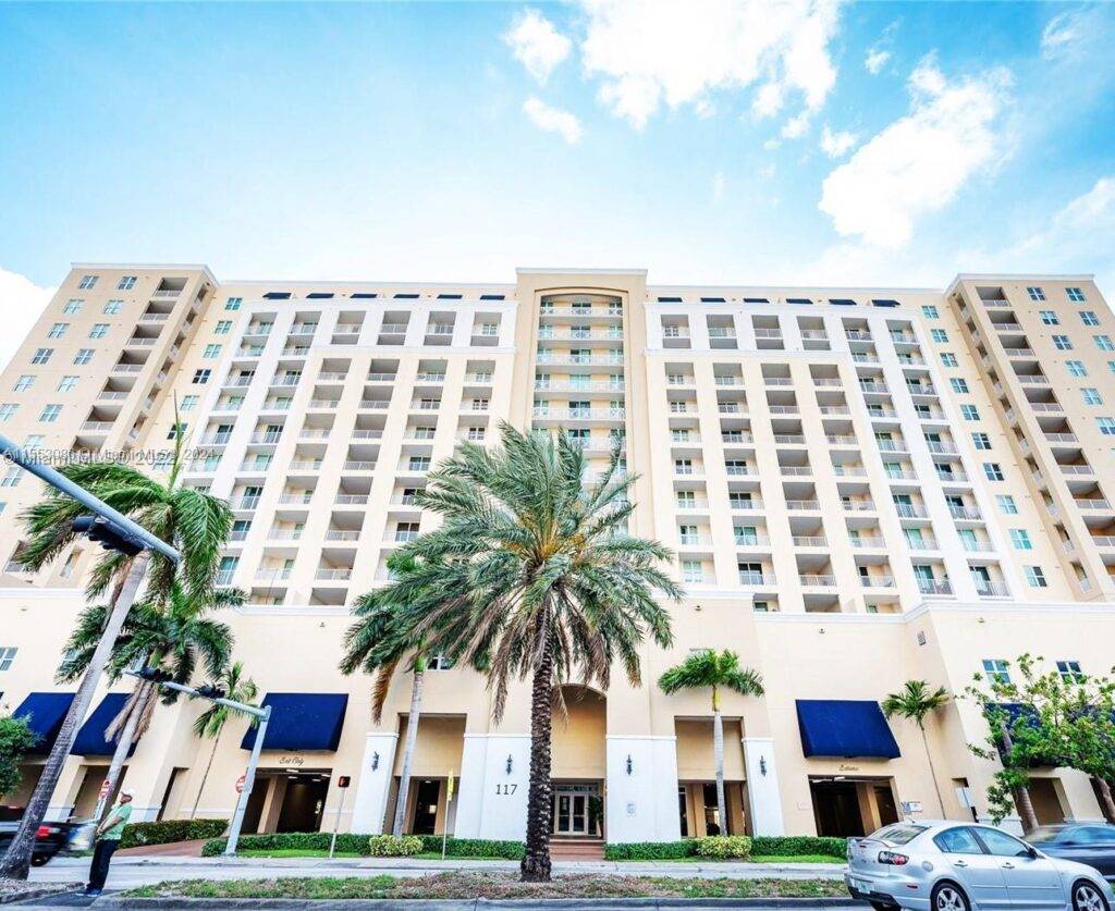Mediterranean-style high-rise building with palm trees and blue sky.