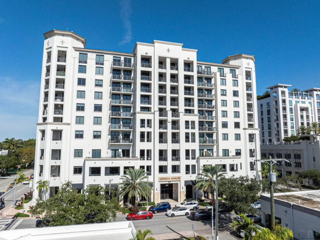 Elegant high-rise building with palm trees in front under a clear blue sky.