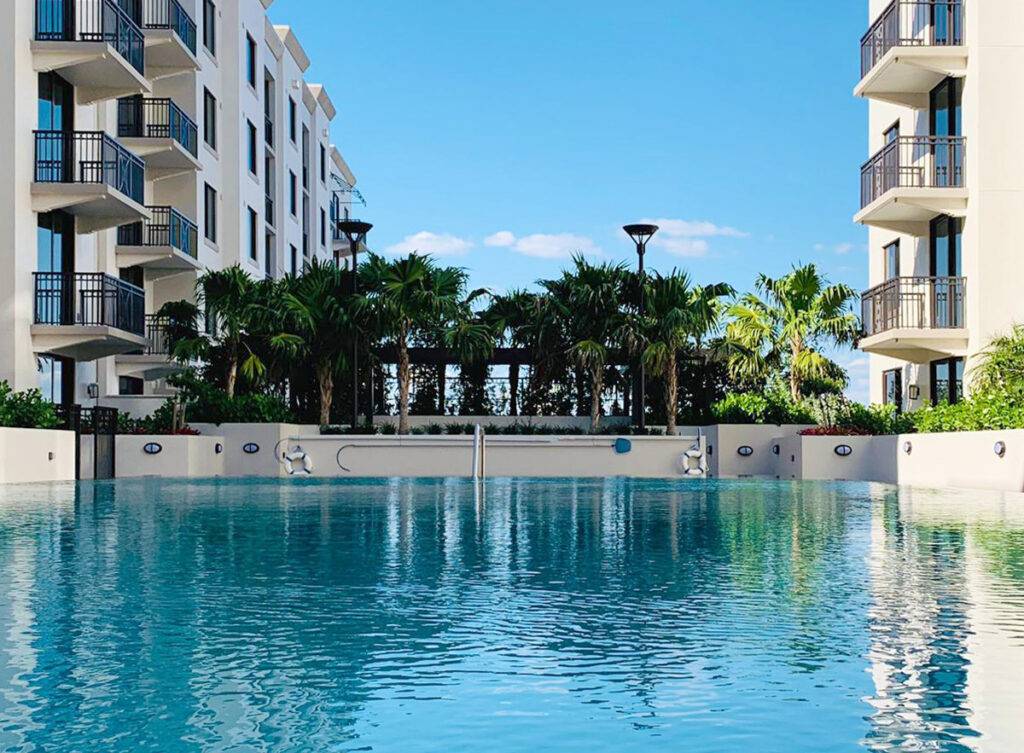 Luxury apartment pool with modern balconies and palm trees.
