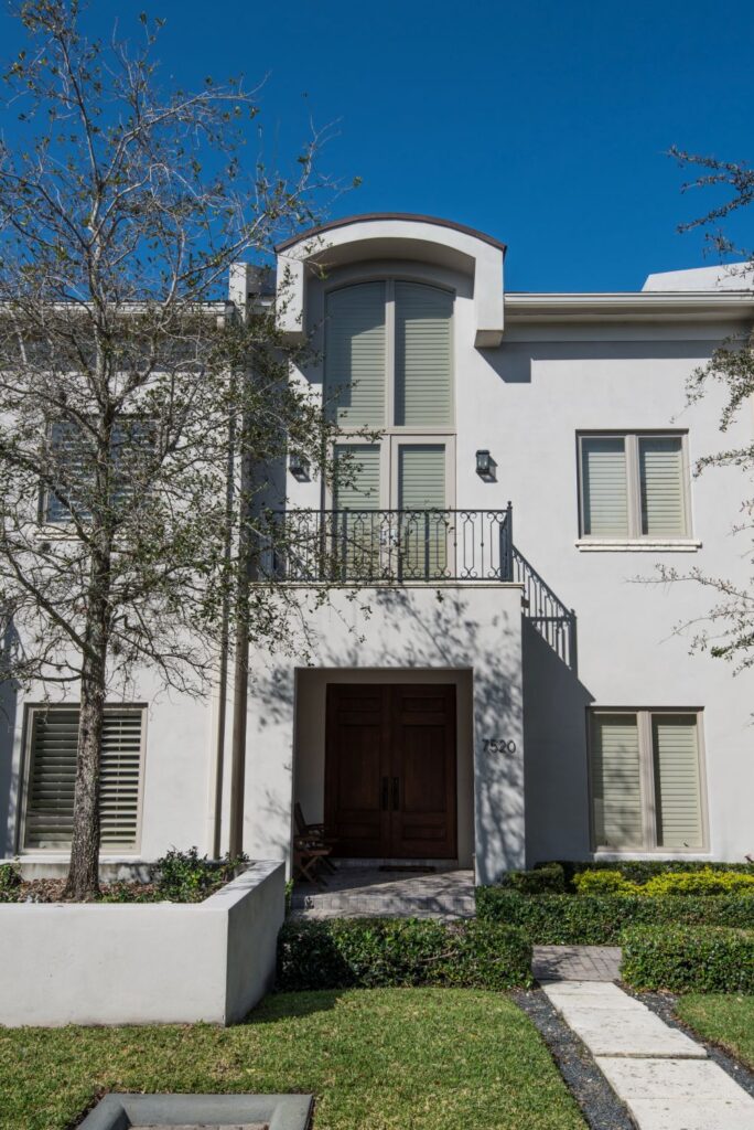 Modern white house exterior with large windows and well-manicured lawn.