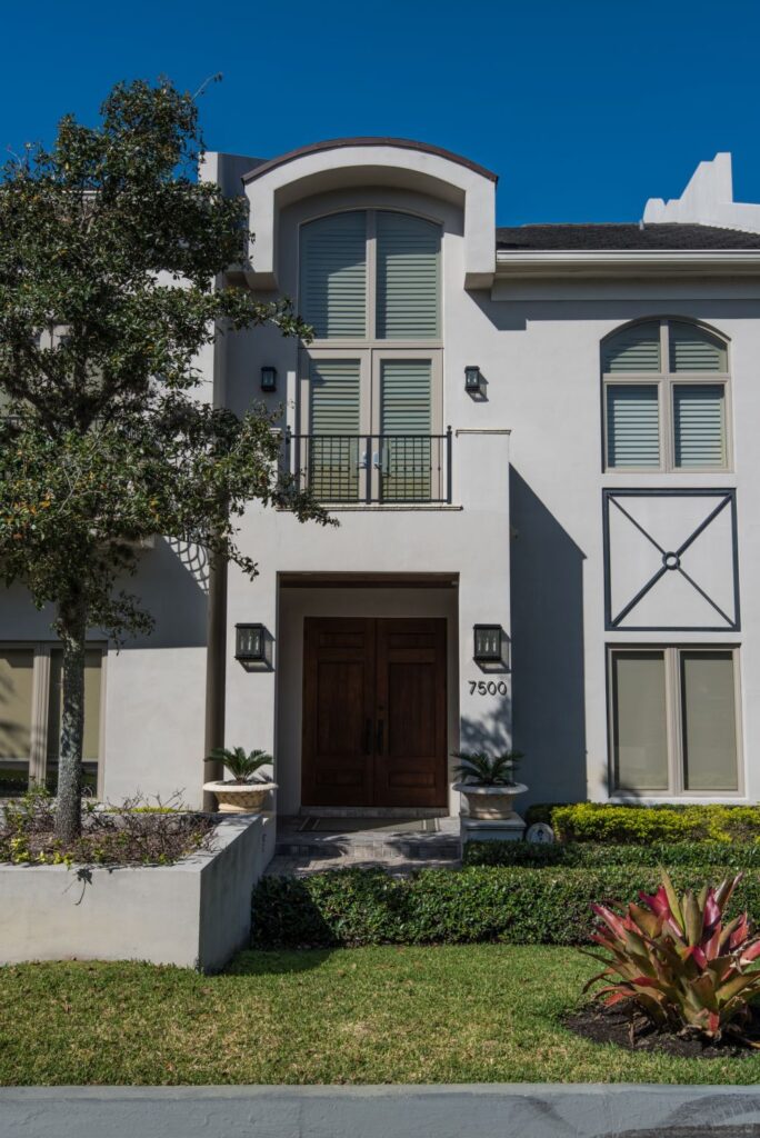 Elegant two-story modern house with large windows and lush landscaping.