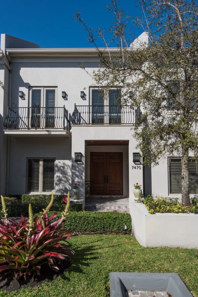 Modern two-story house with a wooden door and lush garden