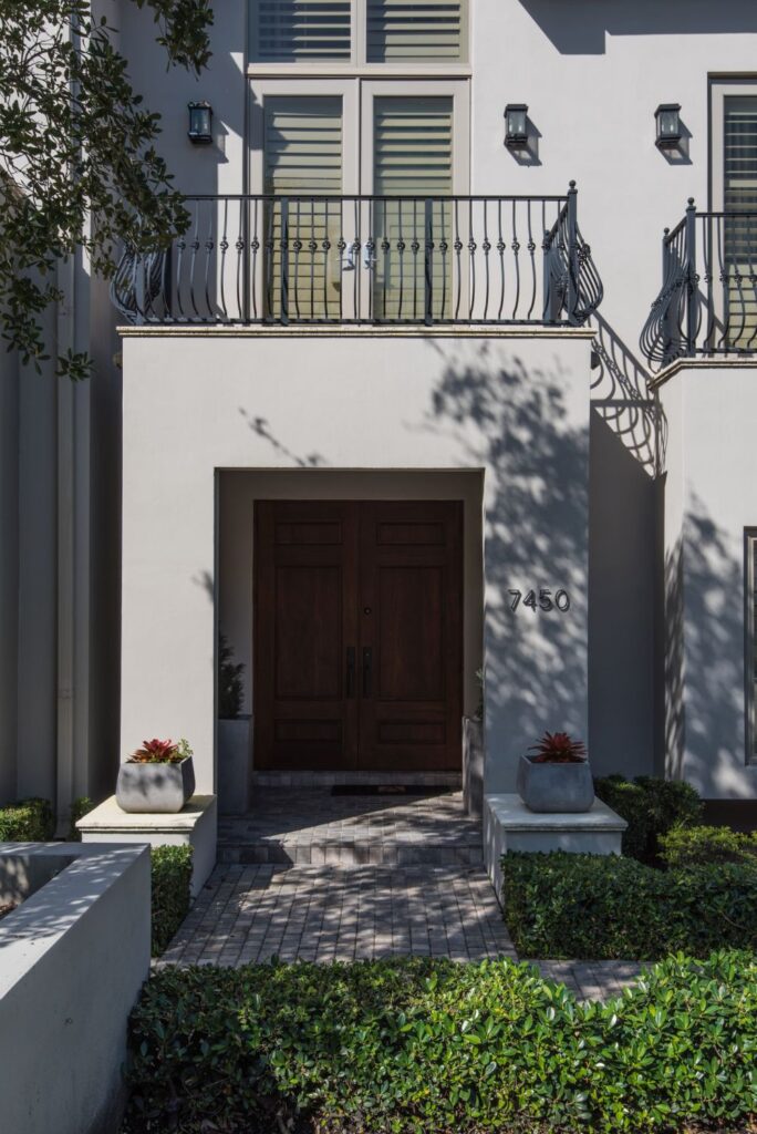 Modern house entrance with double doors and elegant balcony.