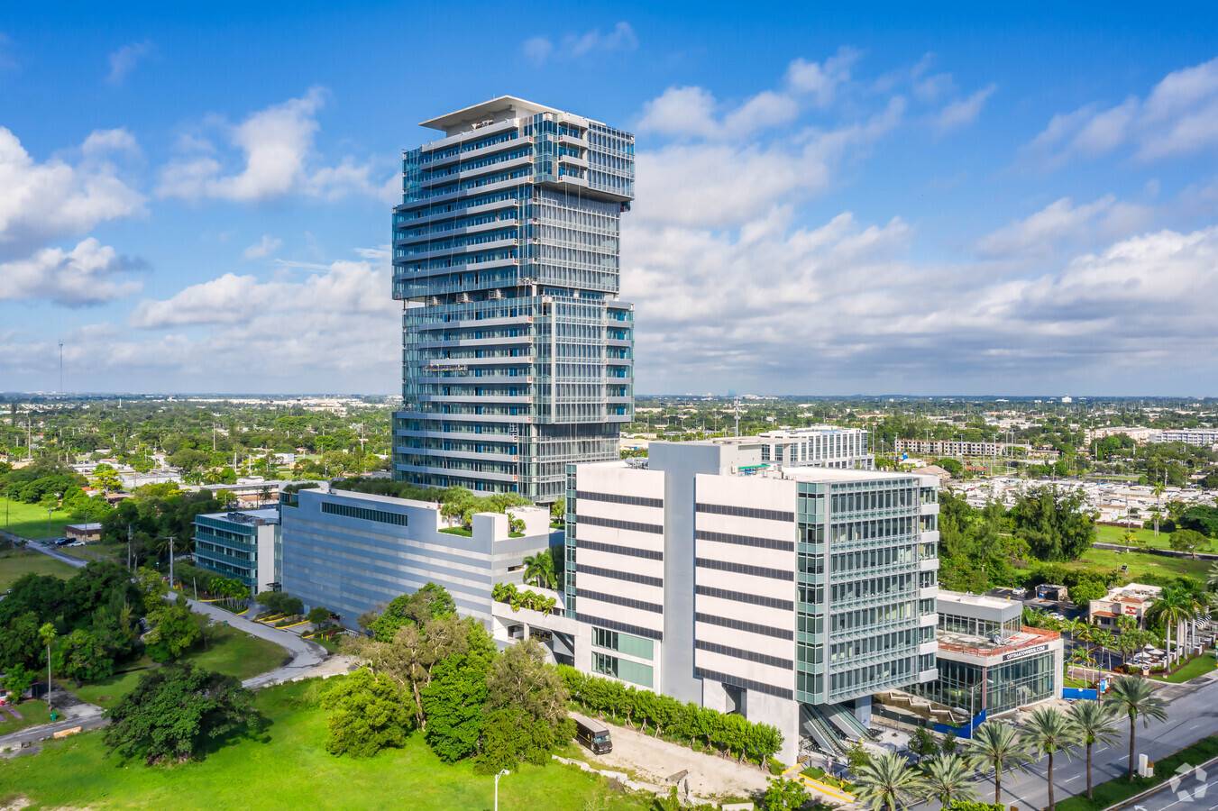 Modern high-rise building with lush greenery and clear blue sky