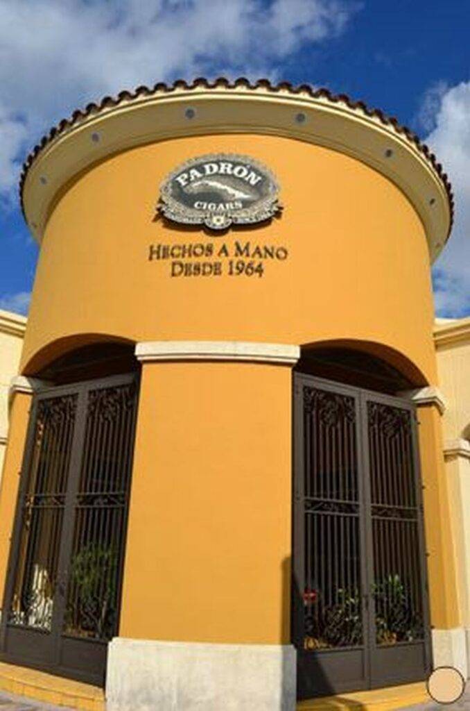 Padrón Cigars building with a yellow facade and ornate signage under a blue sky.
