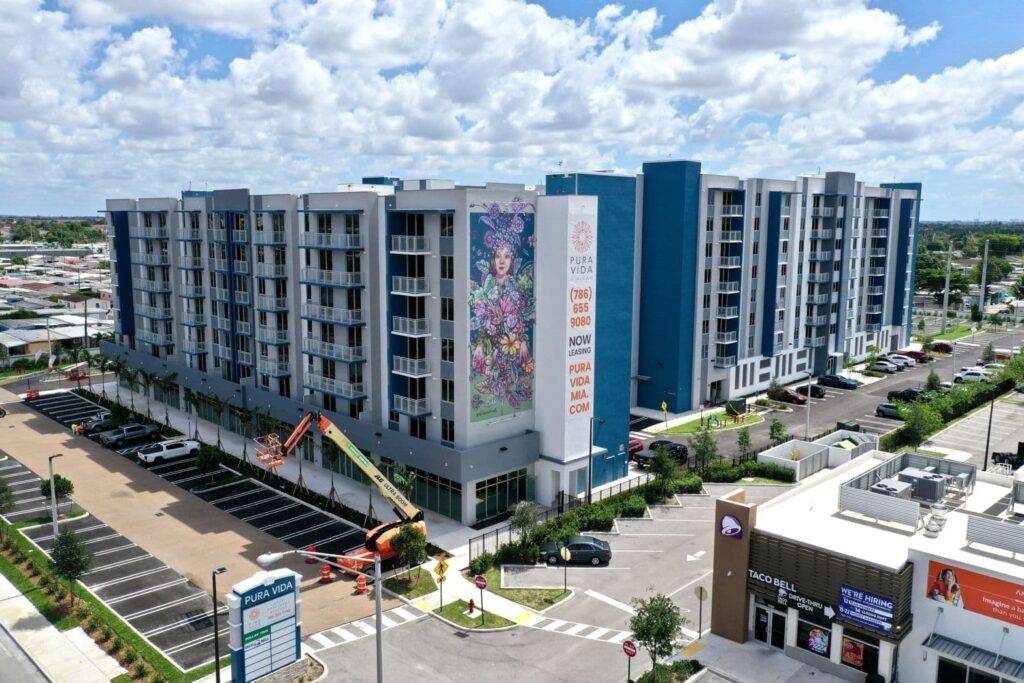 Urban apartment complex with vibrant mural under a blue sky.