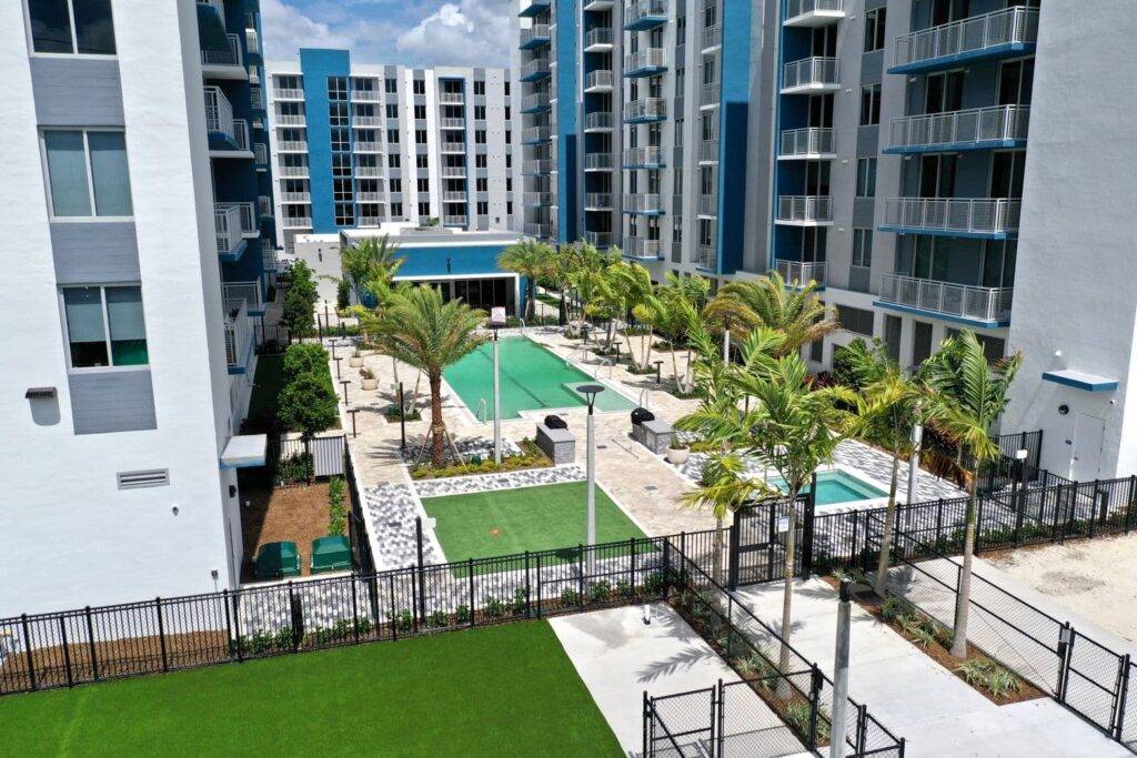 Modern apartment complex with pool and palm trees in central courtyard.