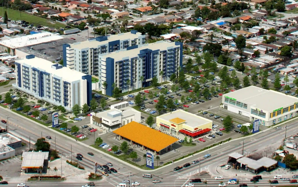 Aerial view of modern urban development featuring a large residential building and adjacent commercial spaces.