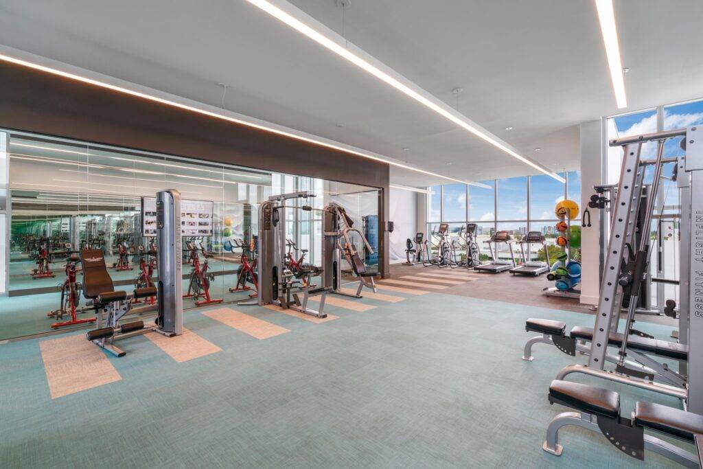 Spacious modern gym with various exercise equipment and large windows.