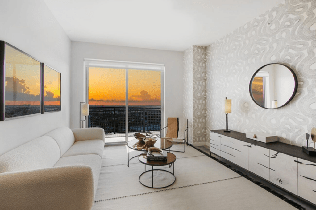 Modern living room with white furniture, large windows, and a stunning sunset view.