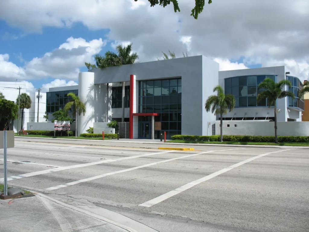 Modern office building on a sunny day with palm trees and a clear sky.