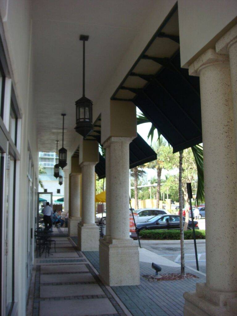 Elegant outdoor walkway in a modern retail plaza with classic columns and street view.