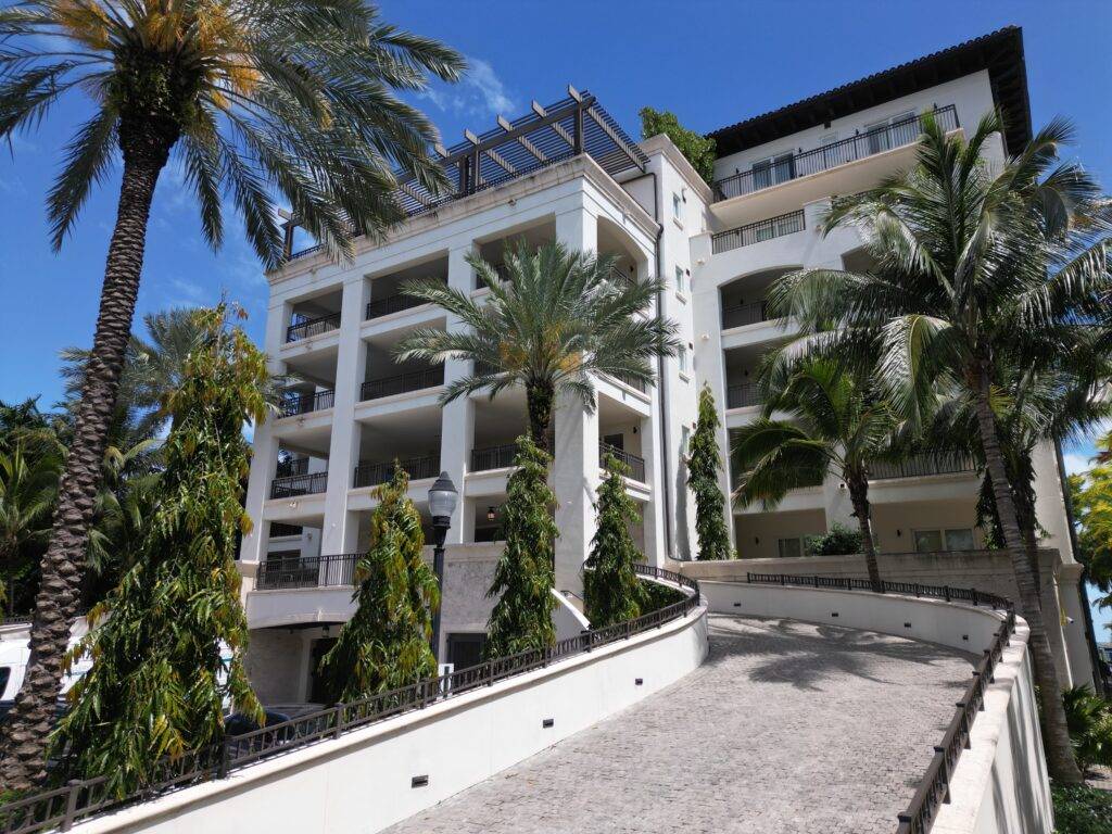 Luxury apartment building surrounded by palm trees against a clear blue sky.