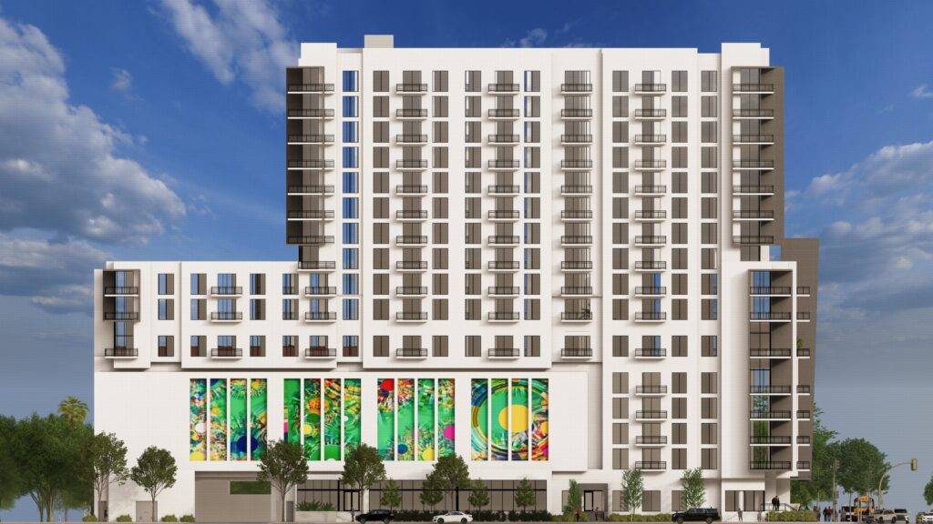 Modern high-rise building with colorful mural and balconies under a blue sky.