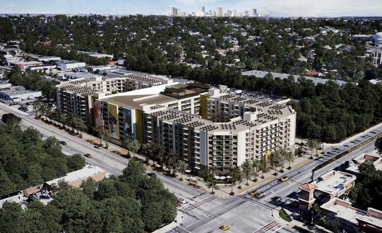 Aerial view of a large urban apartment complex surrounded by greenery and cityscape.