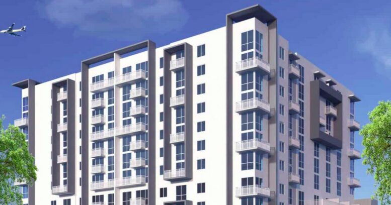 Modern multi-story apartment building with a sleek design and balconies against a clear blue sky.