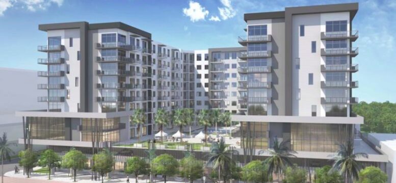 Modern apartment complex with palm trees under a bright blue sky.