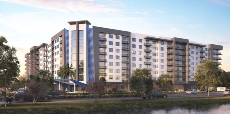 Modern apartment building with balconies and adjacent greenery under a blue sky.