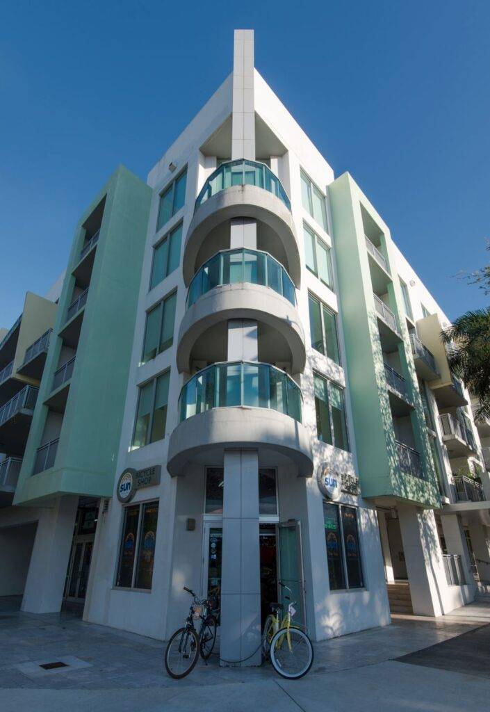 Modern apartment building with balconies and bicycles in front.
