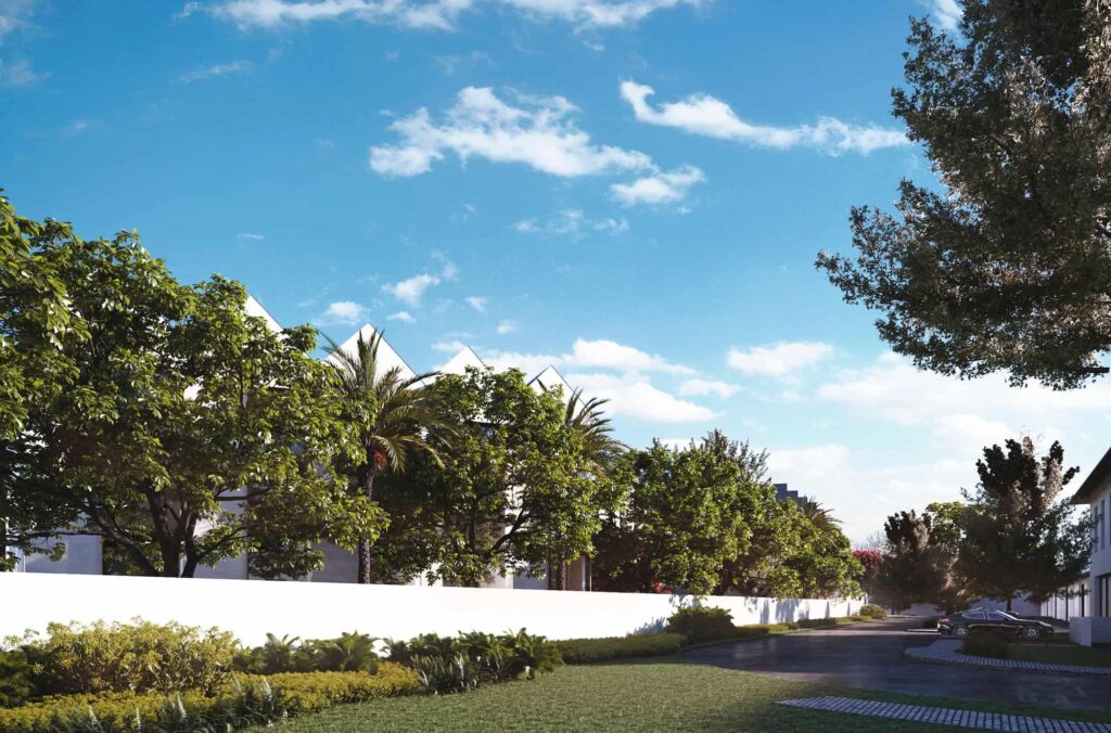 Lush green garden beside a modern white fence under a clear blue sky.