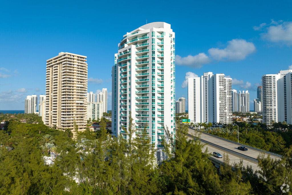 Luxurious high-rise buildings surrounded by lush greenery under a clear blue sky.