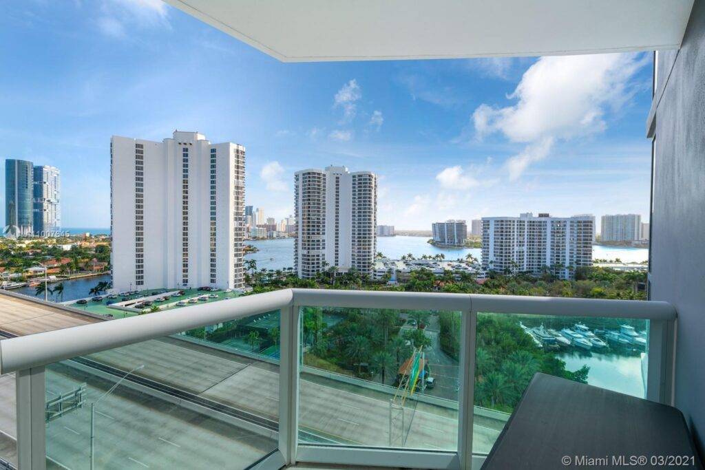 Scenic cityscape view from a high-rise balcony overlooking modern skyscrapers and a vibrant urban landscape under a clear blue sky.