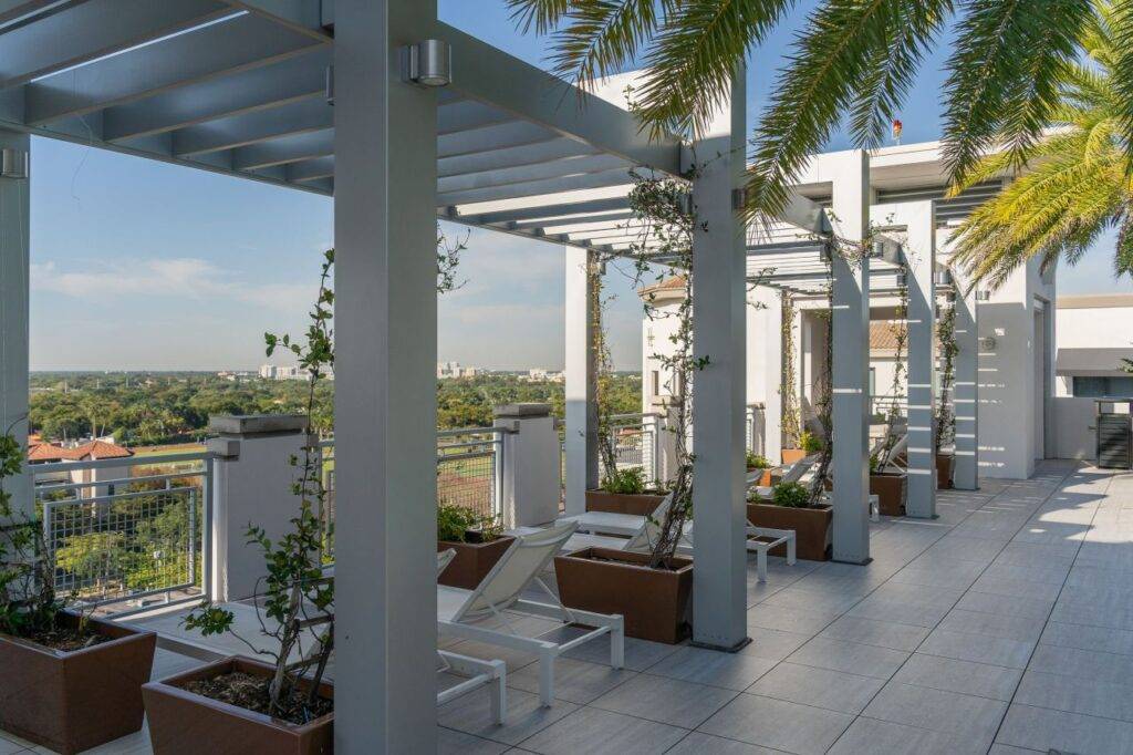 Modern rooftop terrace with pergolas and palm trees overlooking a scenic view.