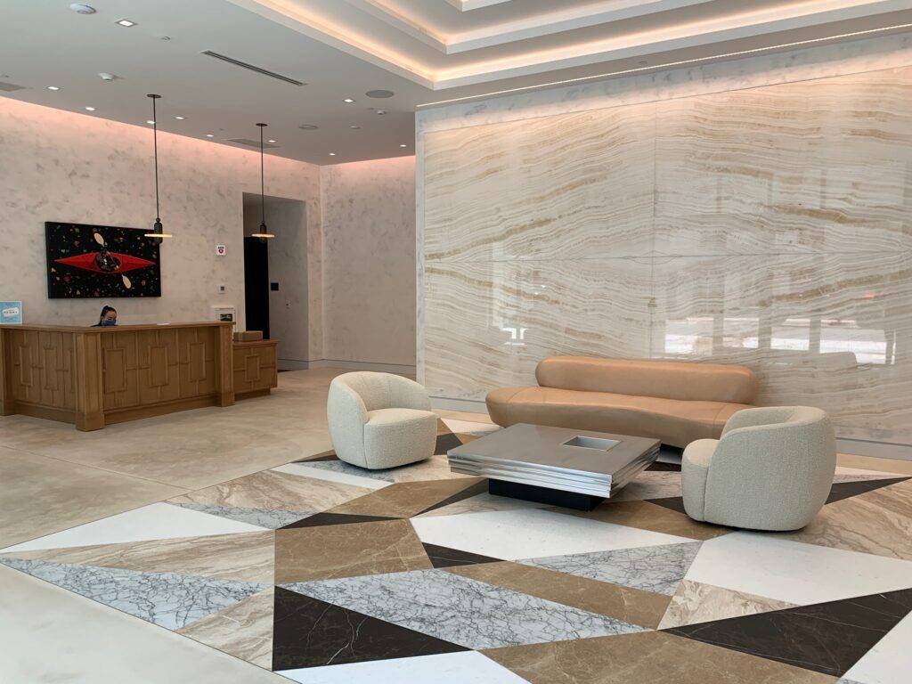 Luxurious modern lobby with marble walls, geometric floor design, and stylish furniture.
