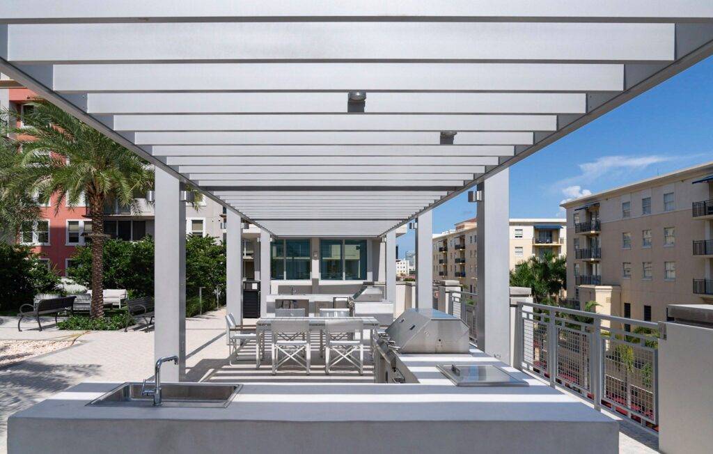 Modern outdoor kitchen area with sleek pergola and urban residential backdrop.