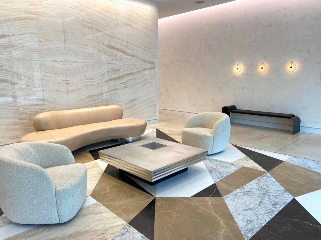 Modern lobby with beige sofas, geometric tiles, and subtle lighting.