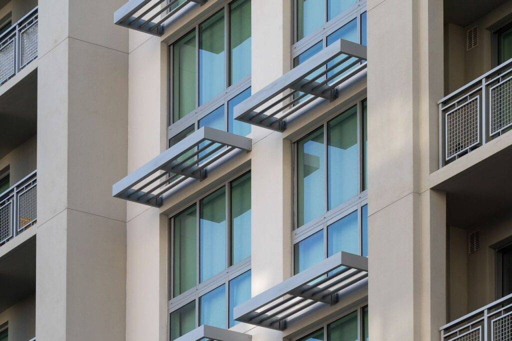Modern building facade with large blue-tinted windows and metal sunshades.