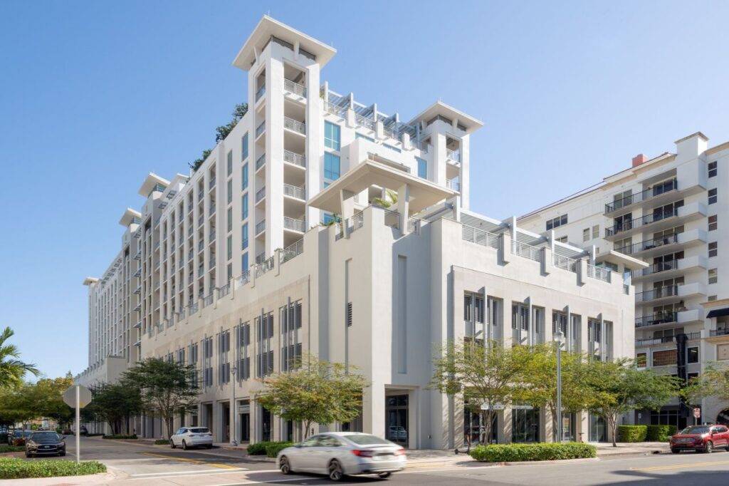 Modern urban apartment building with sleek architecture under a clear blue sky.