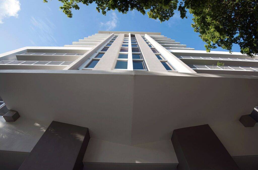 Low-angle view of a modern skyscraper against a clear blue sky.