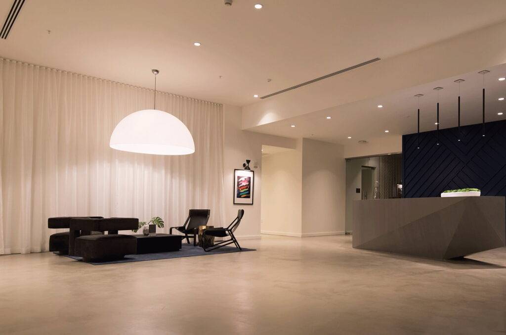 Modern hotel lobby with minimalist design featuring a stylish seating area and large pendant light.