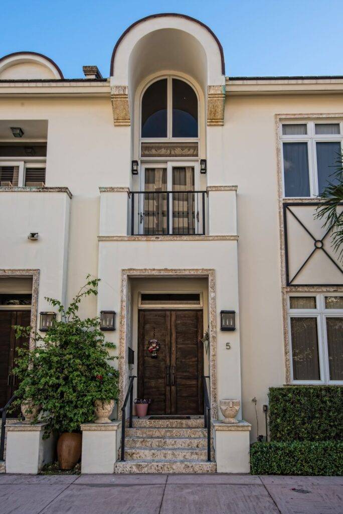 Elegant Valencia Village facade featuring arched windows and lush greenery.