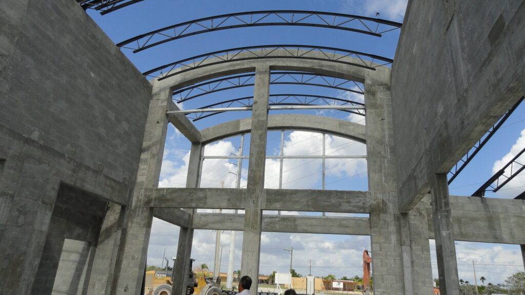 Modern building construction site under a blue sky with steel beams and unfinished concrete walls.