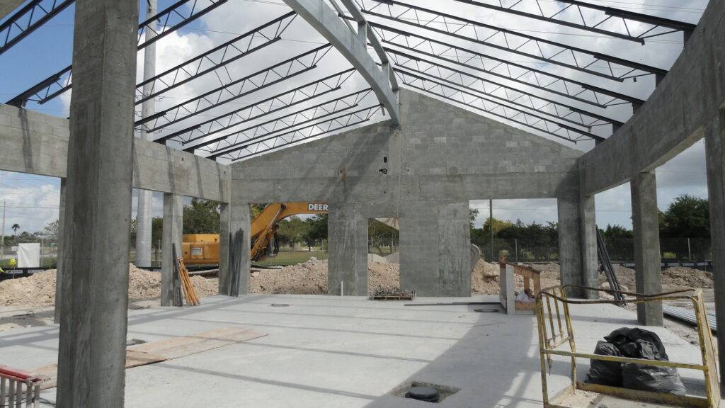 Modern construction site with metal framework and concrete walls under a clear sky.