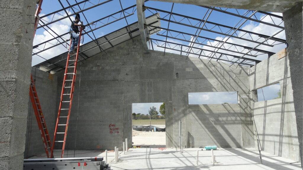 Construction of a concrete structure with large windows and a red ladder.