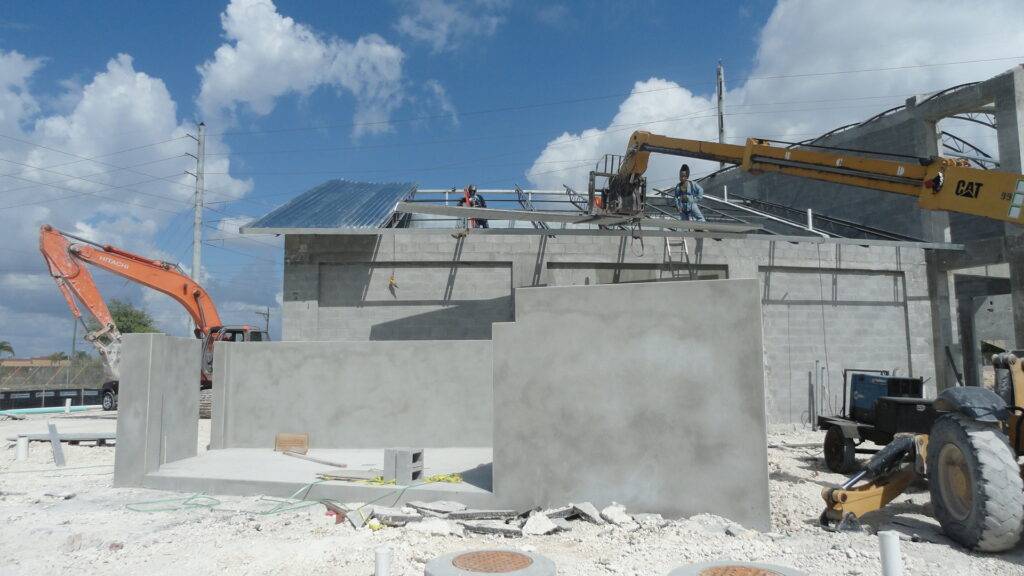 Construction site with machinery and workers assembling a building under a blue sky.