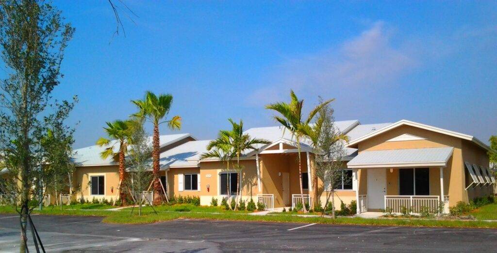 A modern residential building surrounded by palm trees under a clear blue sky.