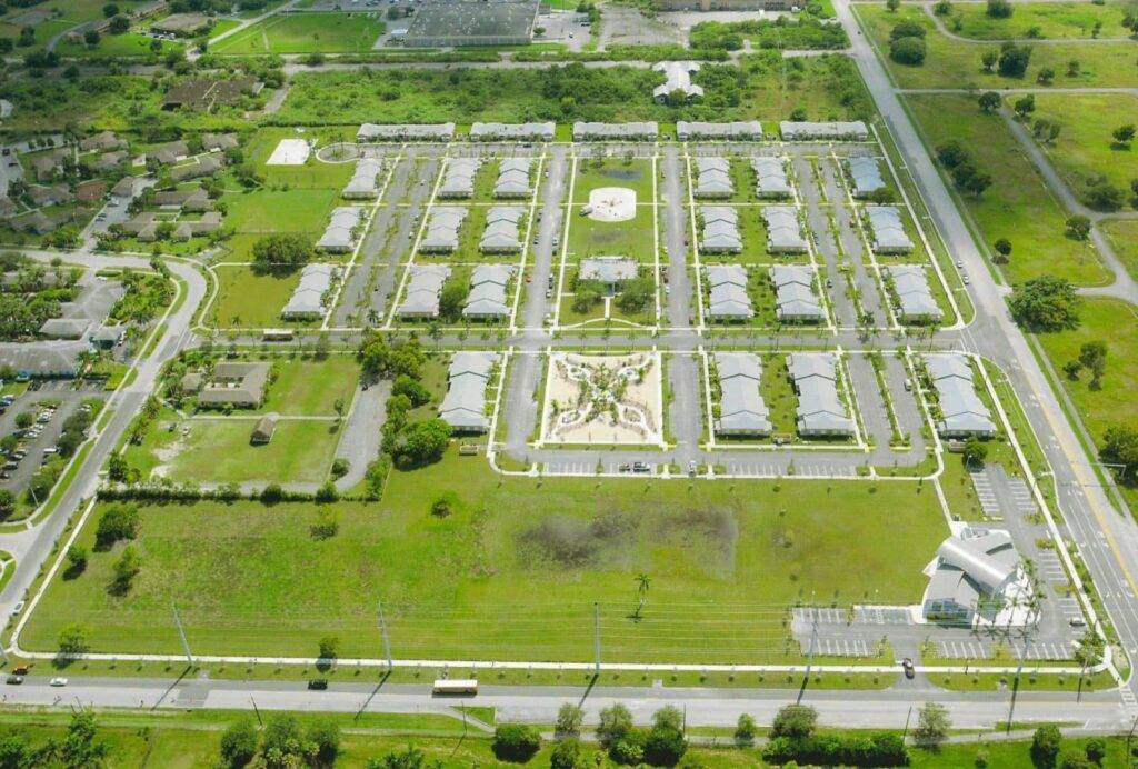 Aerial view of lush green residential community with organized housing layout and surrounding roads.