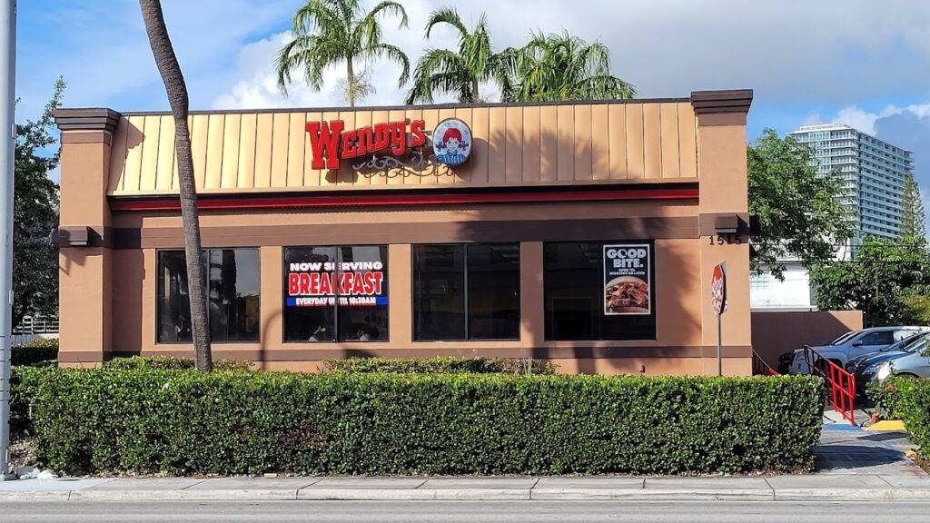 Wendy's restaurant with open sign, surrounded by lush greenery.