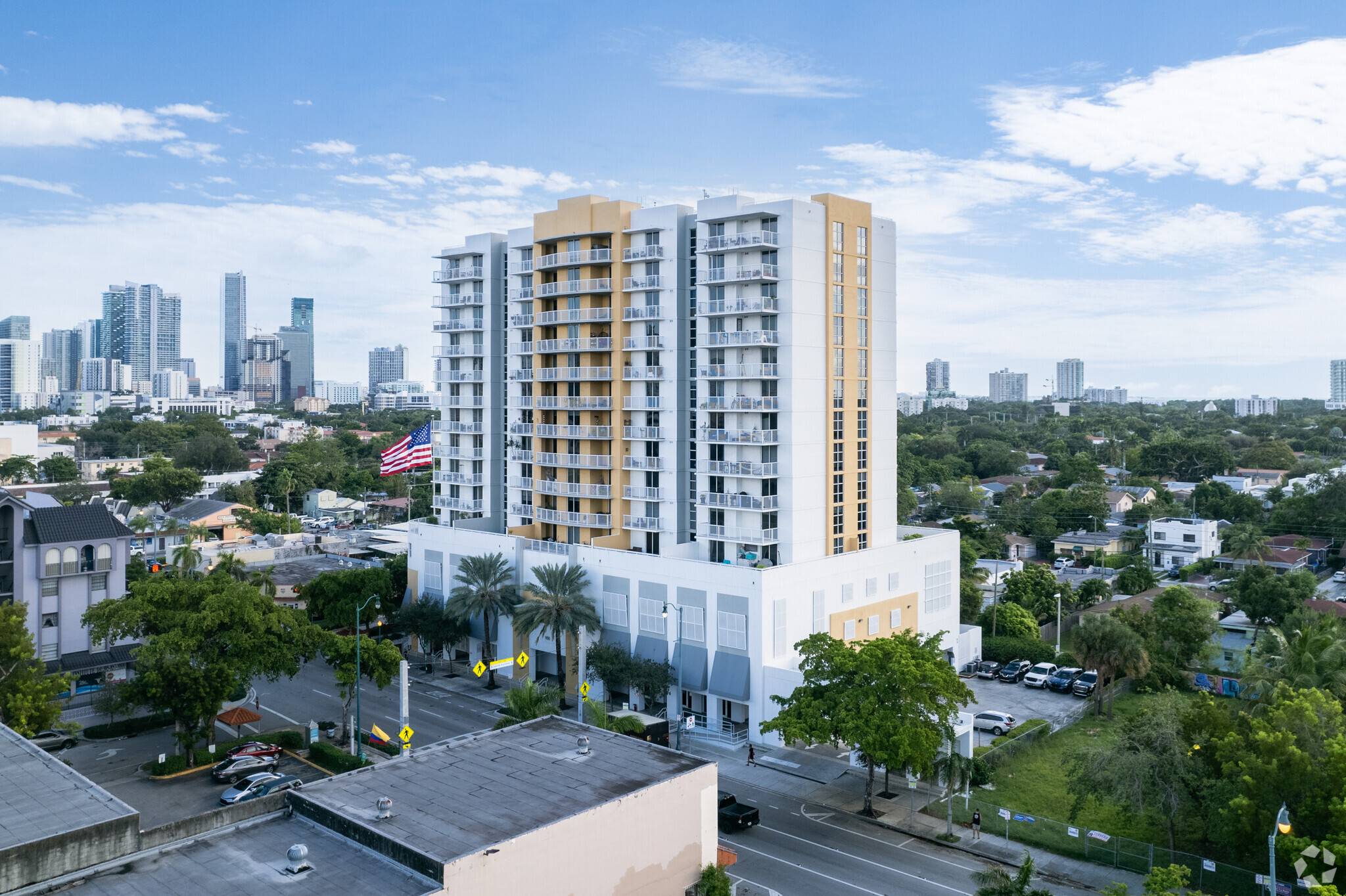 Aerial view of a modern city building with a backdrop of skyscrapers and lush greenery.